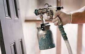 a spray gun shooting out a liquid with a hand pressing down on the trigger