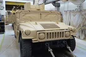 a tan military vehicle in a sterile white room